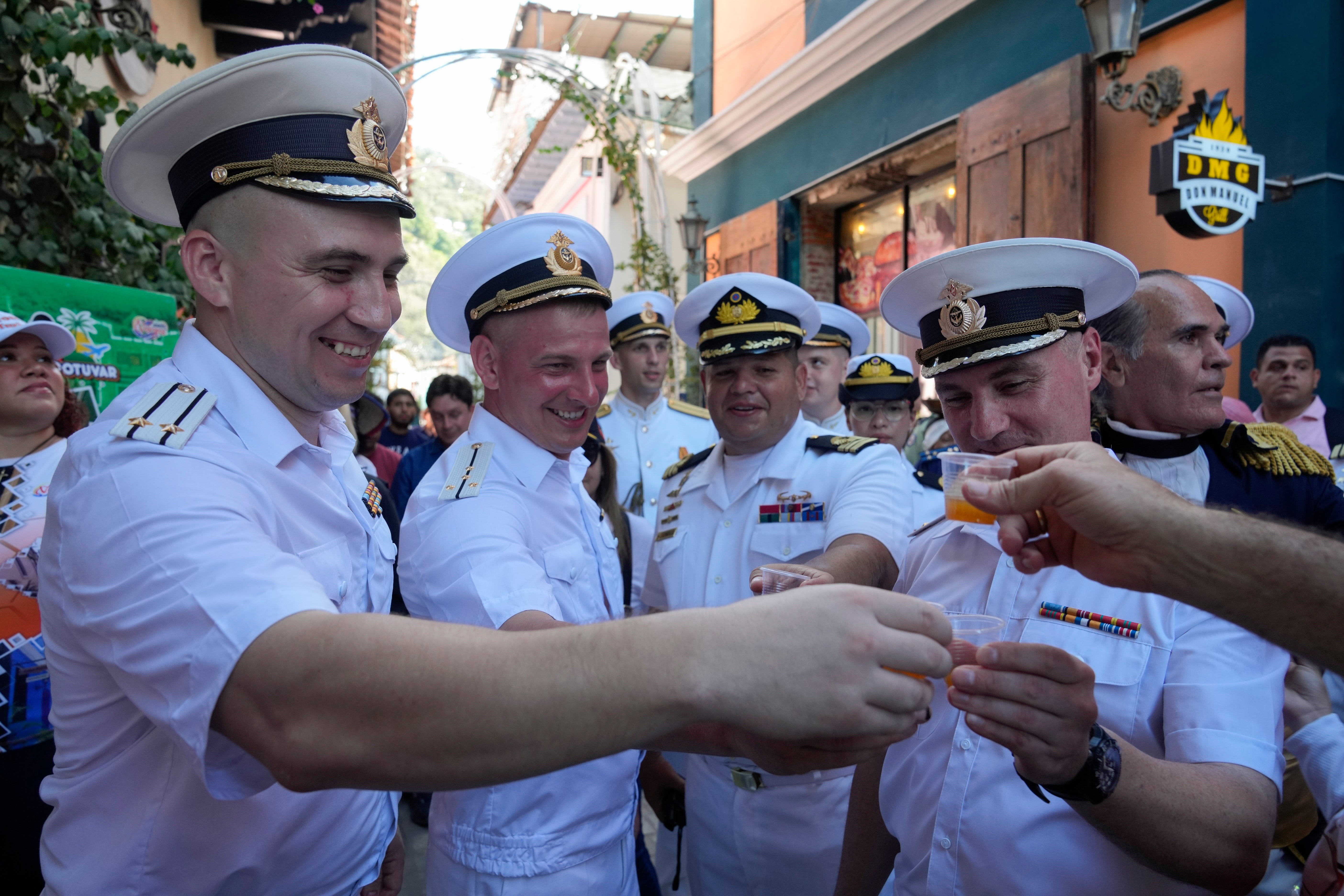 Russian crew members toast with a traditional Venezuelan drink during a welcoming tour by official authorities