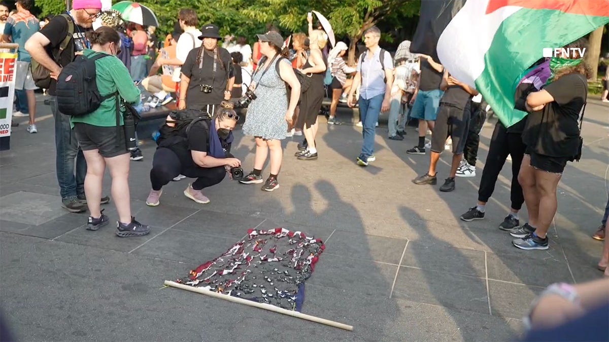 Onlookers stare at a burn U.S. flag