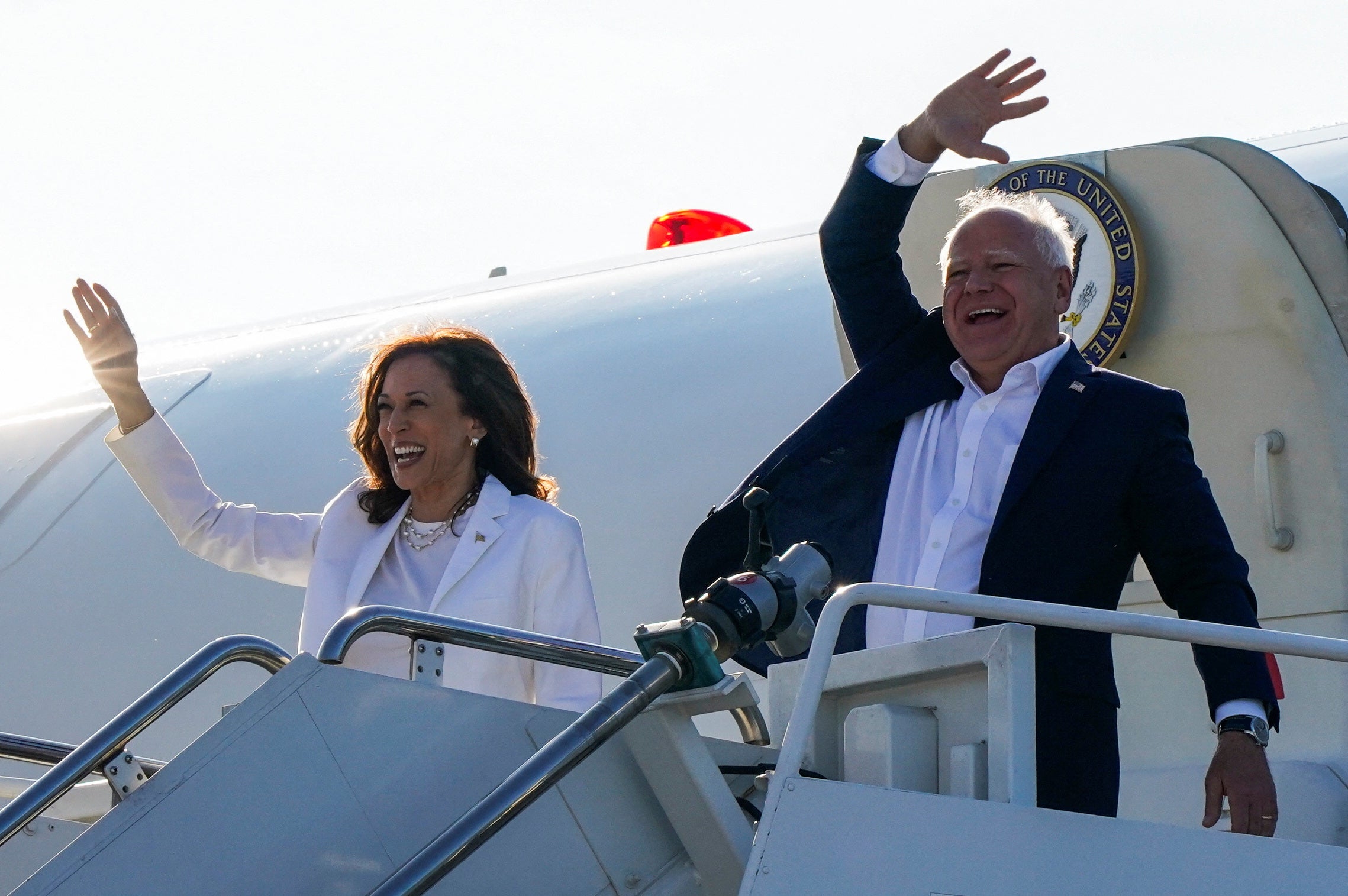 Vice President and Democratic presidential candidate Kamala Harris waves as she walks off the plane with Walz. Some women have taken to social media to describe Walz and compare him to their own fathers.