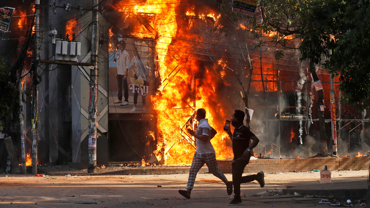 Men run past a shopping center which was set on fire