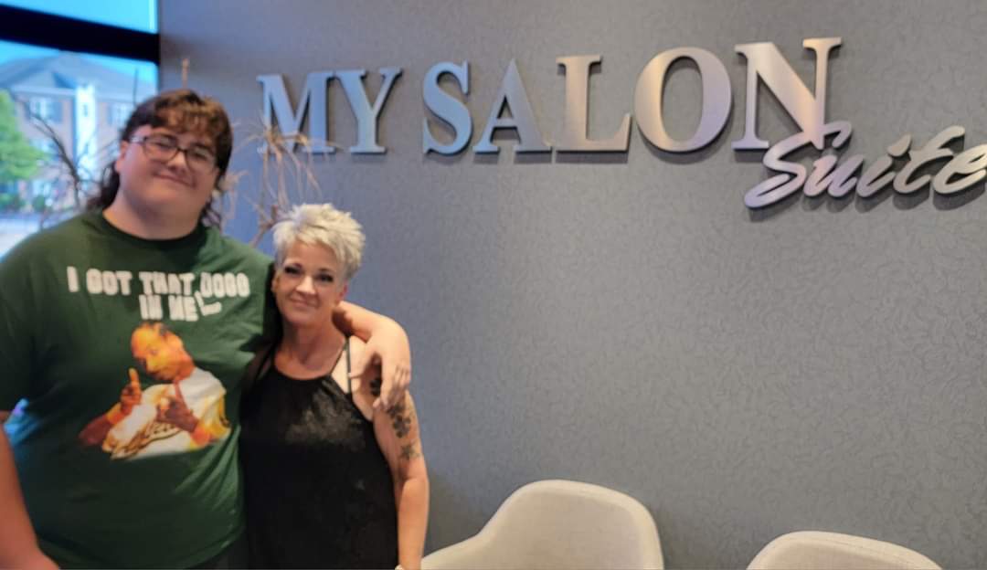 Will Joyner poses with the hairdresser who cuts and helps tain his mullet – though he proudly points out the curls are natural