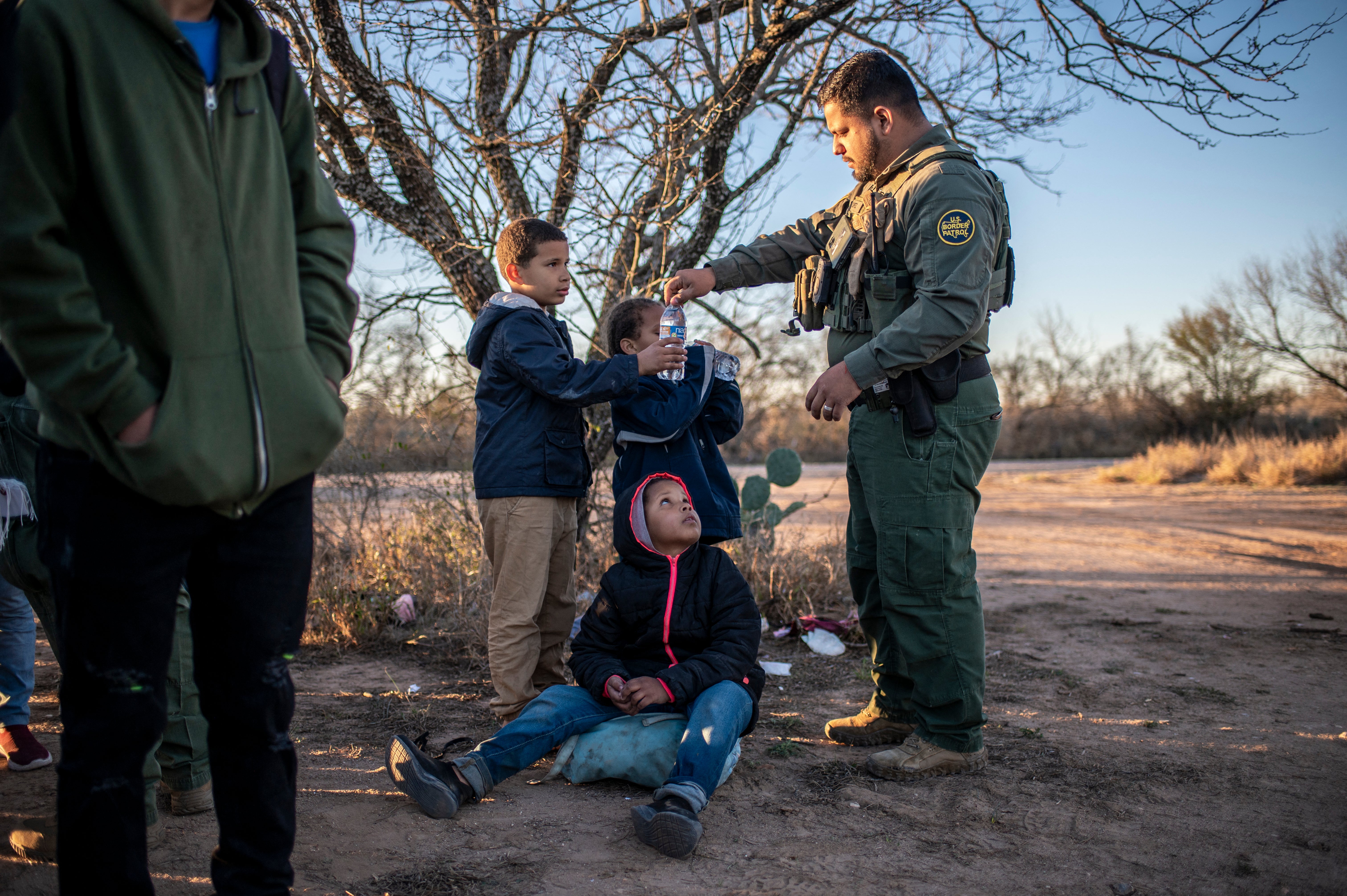 A Border Patrol agent gives a group of unaccompanied minors water after they were apprehended near the highway on February 4, 2024 outside Eagle Pass, Texas