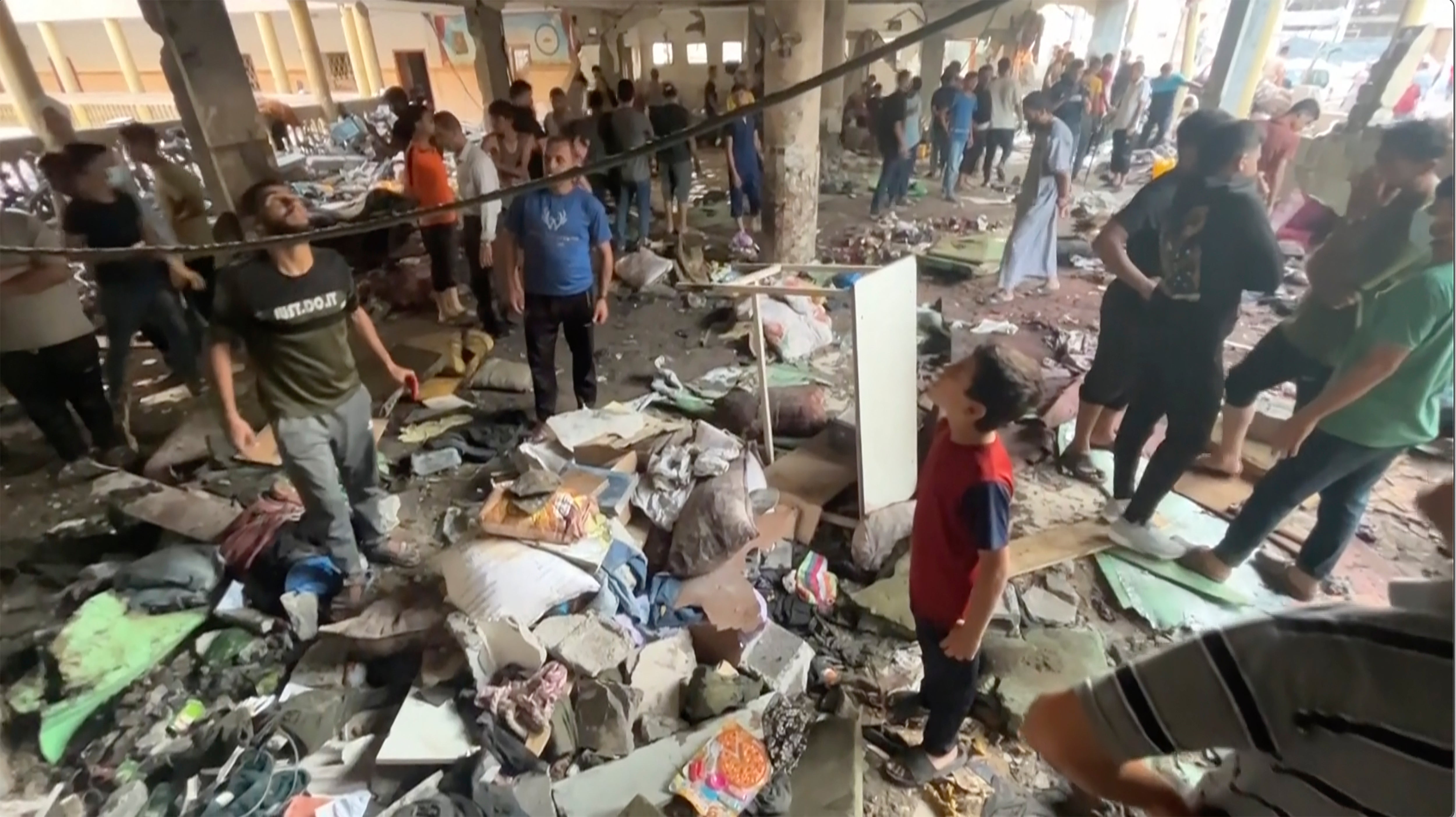 Eyewitnesses inspect the damage after Israeli forces struck a school over the weekend in Gaza City, killing at least 90 people