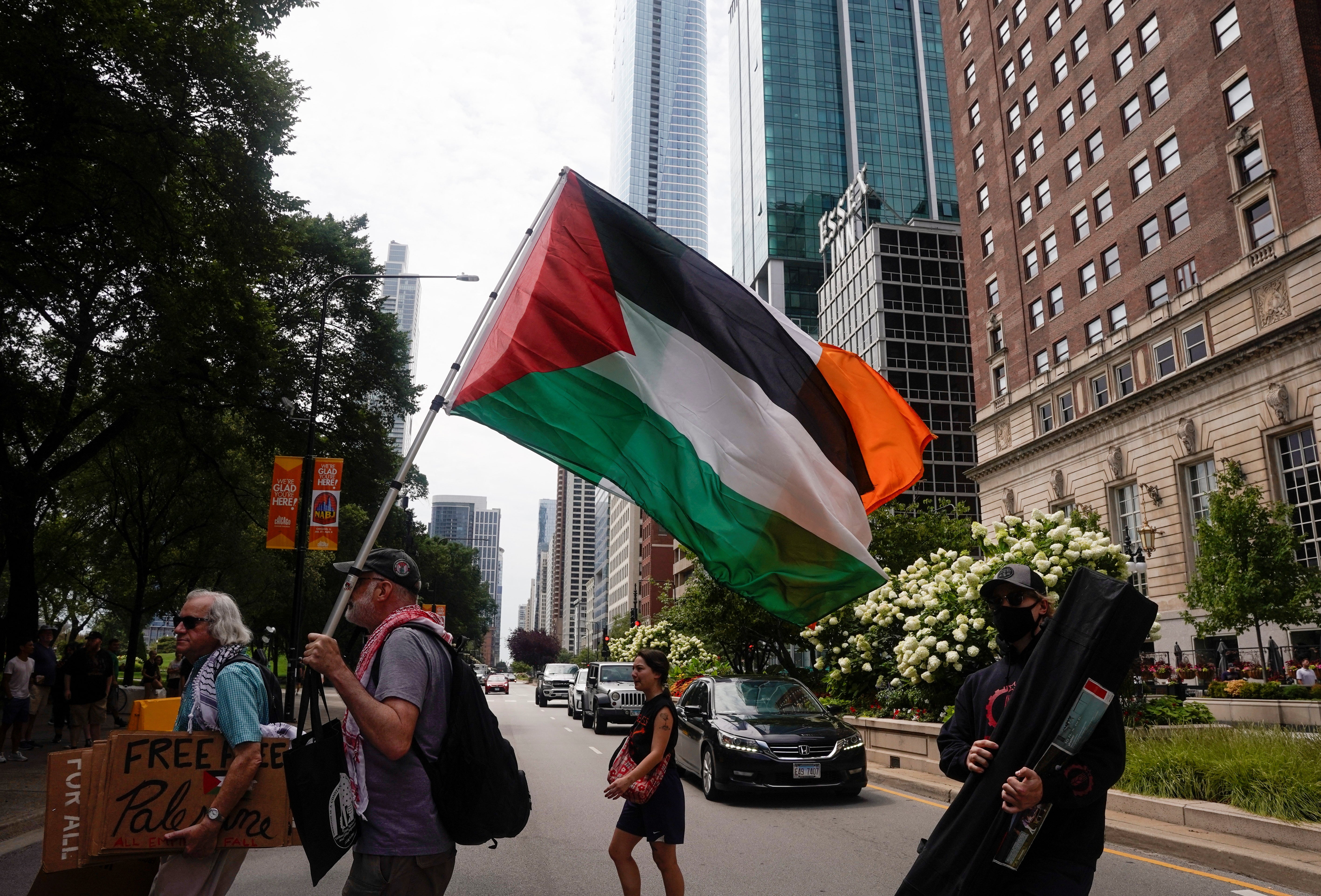 Demonstrators protest against the participation Donald Trump in the National Association of Black Journalists convention, outside the venue in Chicago while holding Palestinian flag on July 31