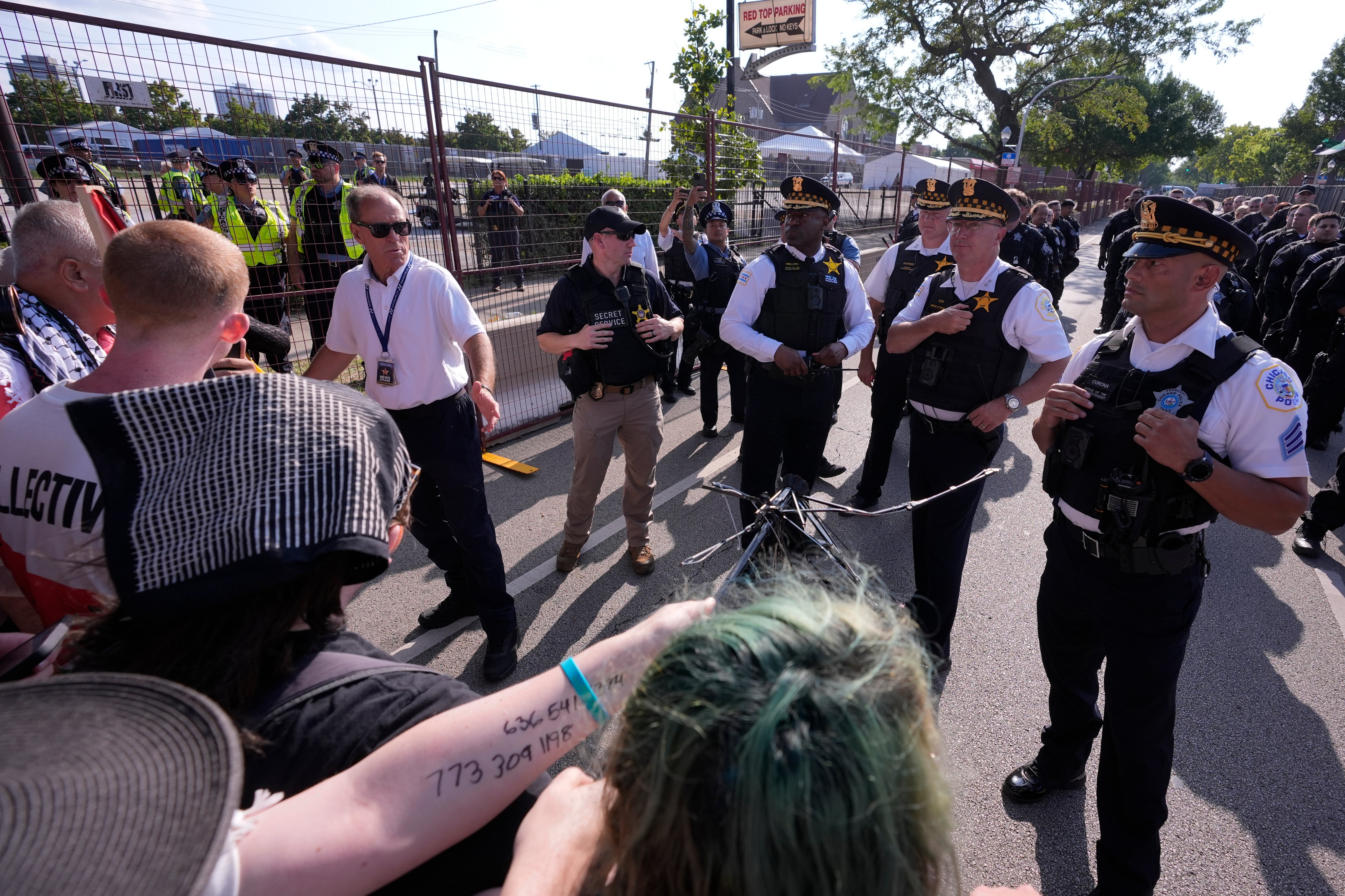 Police walk towards protesters who knock down a fence surrounding United Center at the Democratic National Convention after a march Monday, Aug. 19, 2024, in Chicago