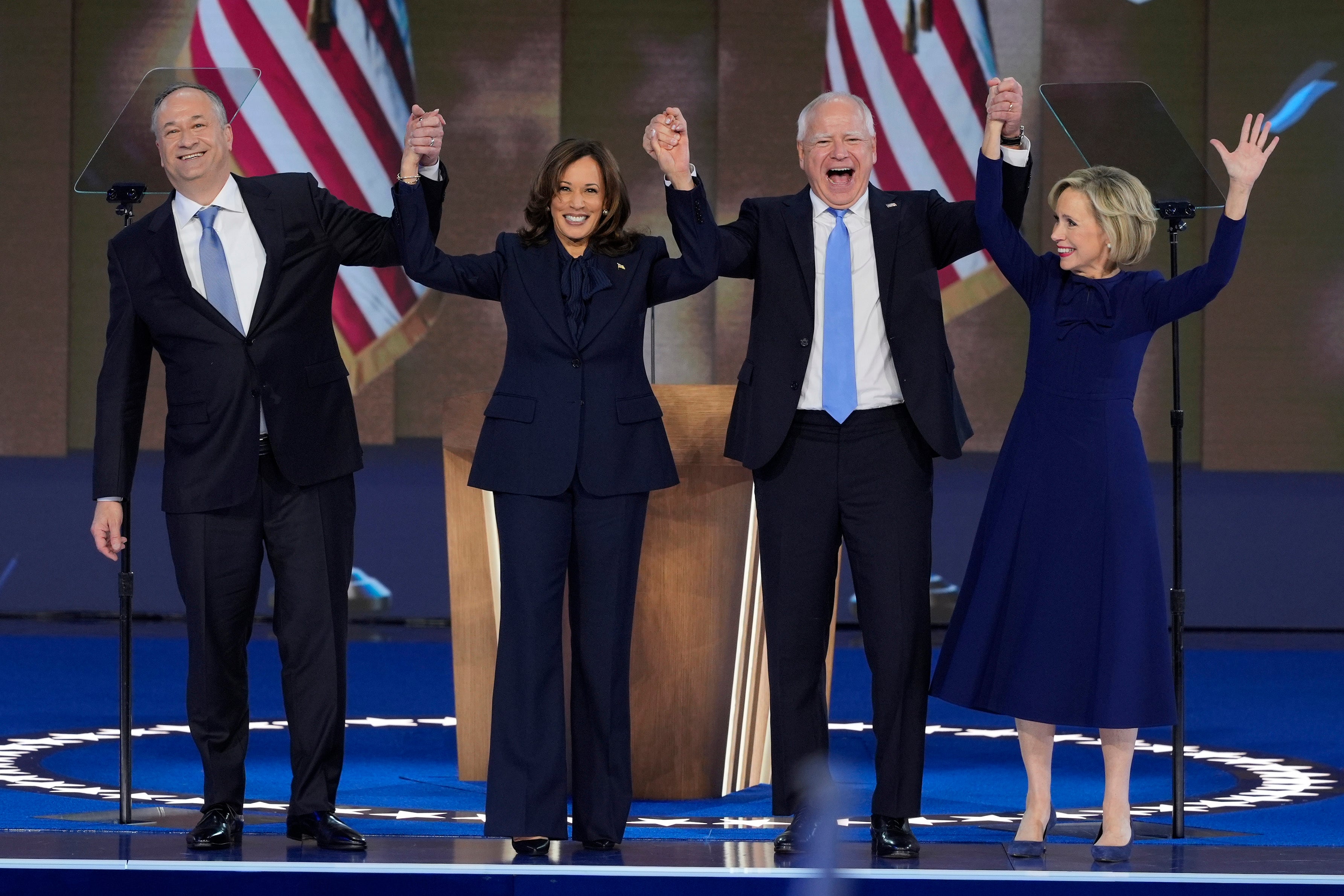 Doug Emhoff, Kamala Harris, Tim Walz and his wife Gwen Walz wave at the Democratic National Convention on August 22.