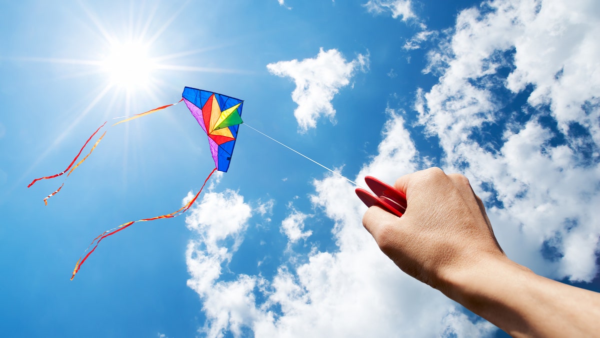 Kite flying in the sky with the sun shining in background