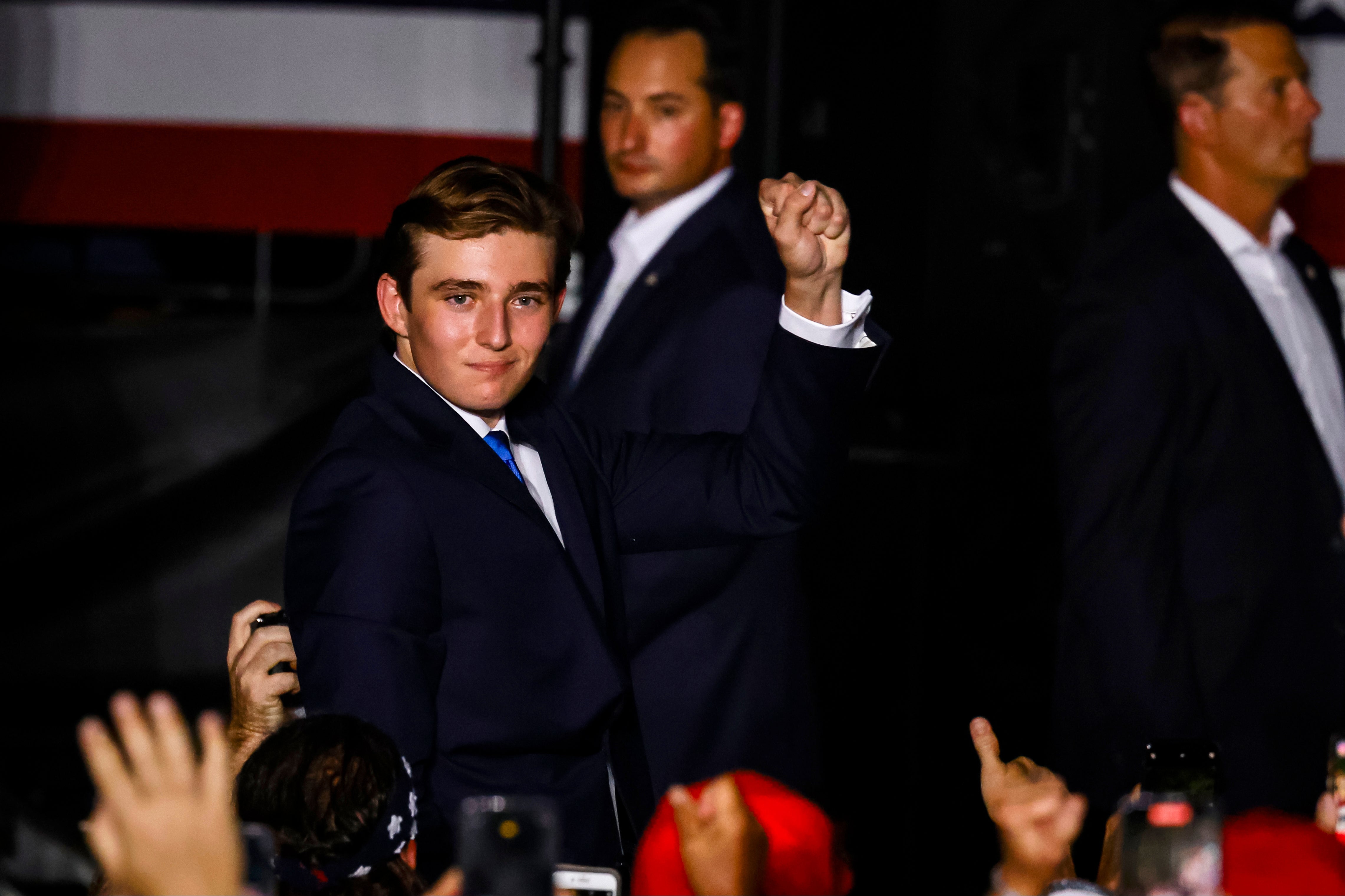 Barron Trump gestures to the crowd at a campaign rally for his dad in July