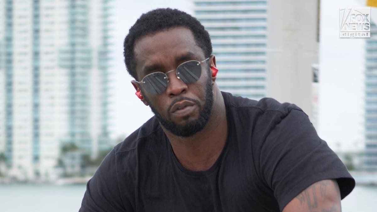 P Diddy looks at the camera wearing sunglasses as he rides his bicycle.