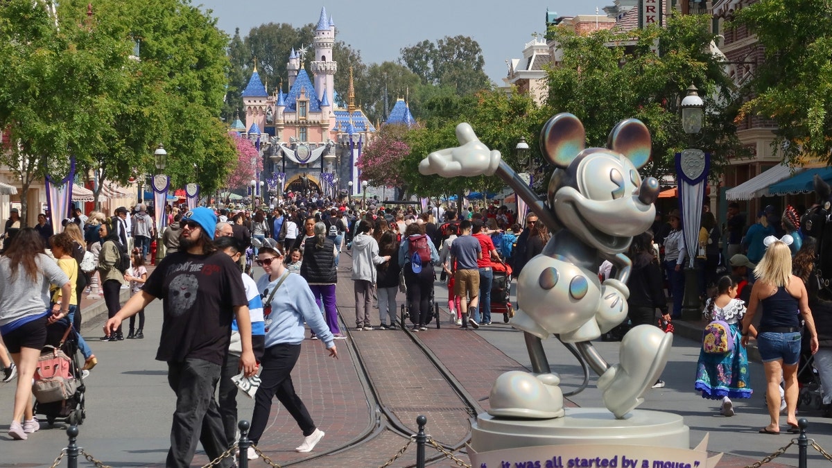 People walk next to Mickey Mouse along Main Street in Disneyland