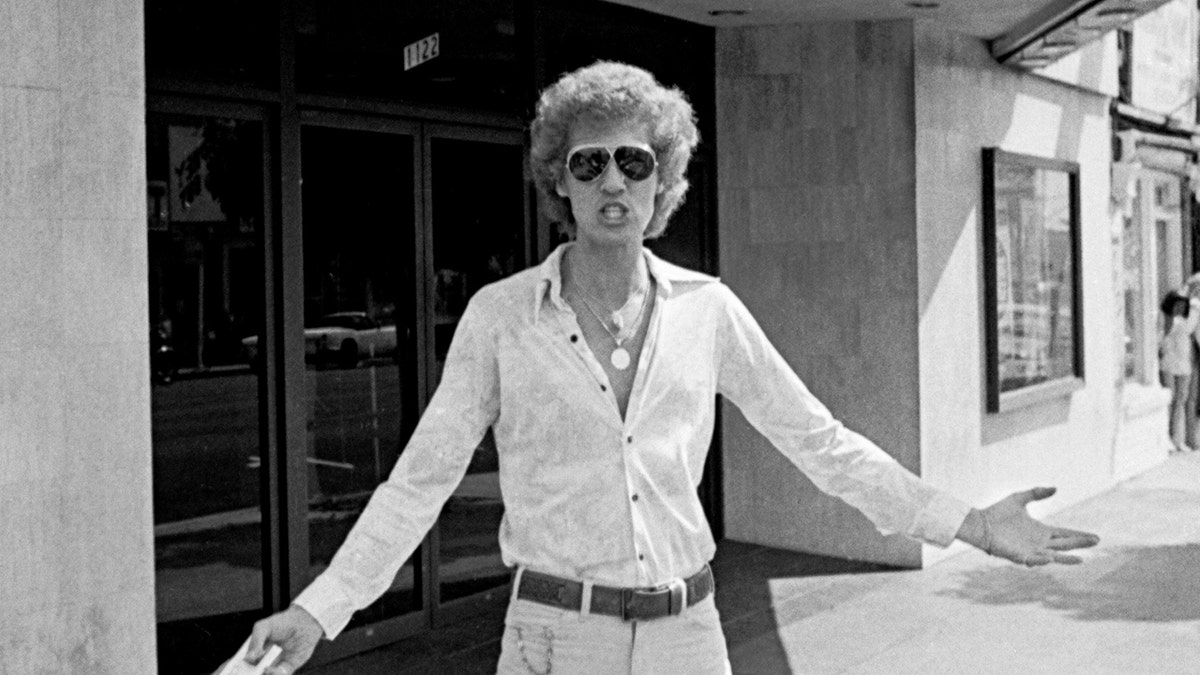 John Holmes wearing sunglasses and a button-down shirt.