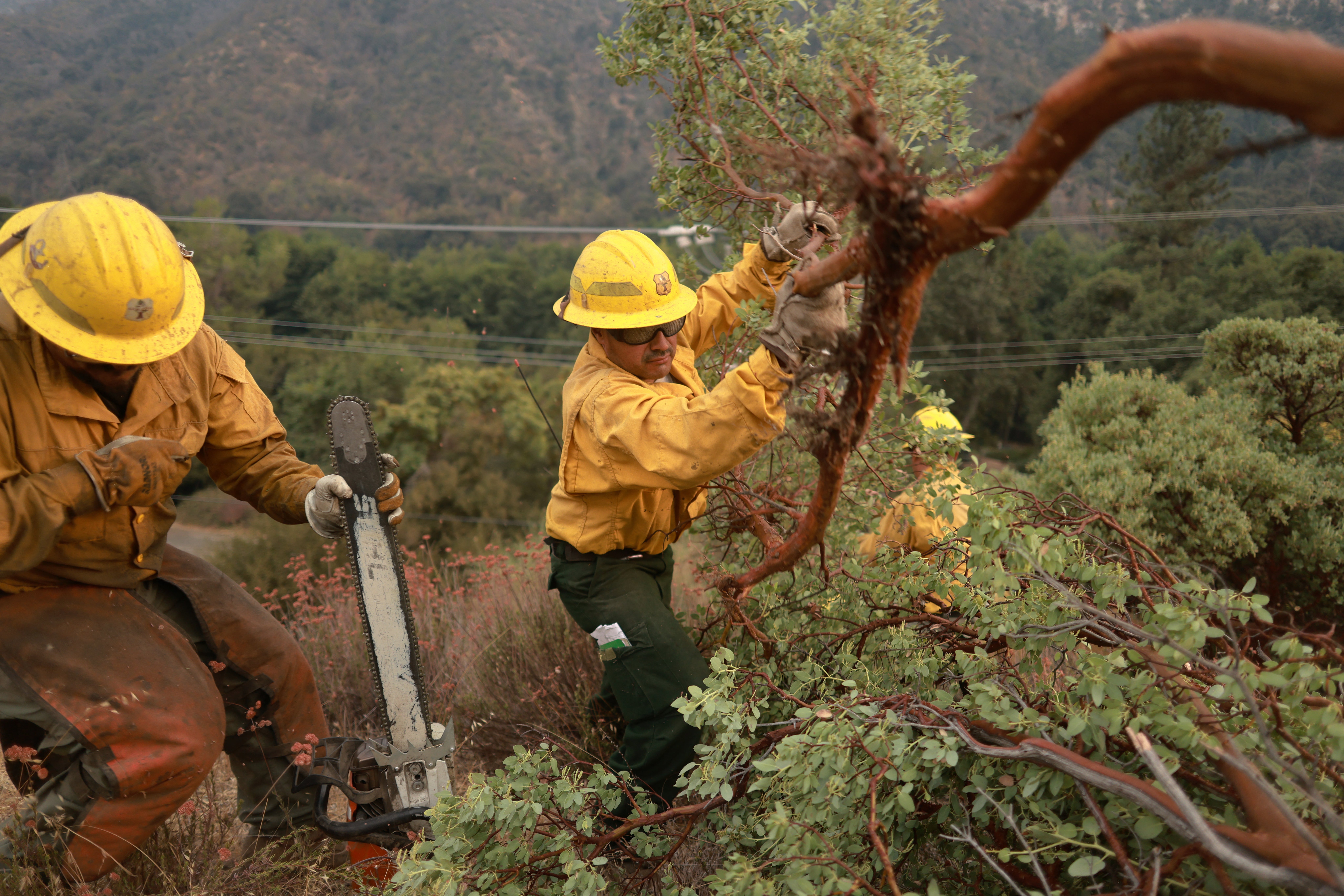 Firefighters work on the Line Fire on Sunday amid extreme weather and severe temperatures. Thunderstorms are expected to pose a challenge to firefighting efforts.