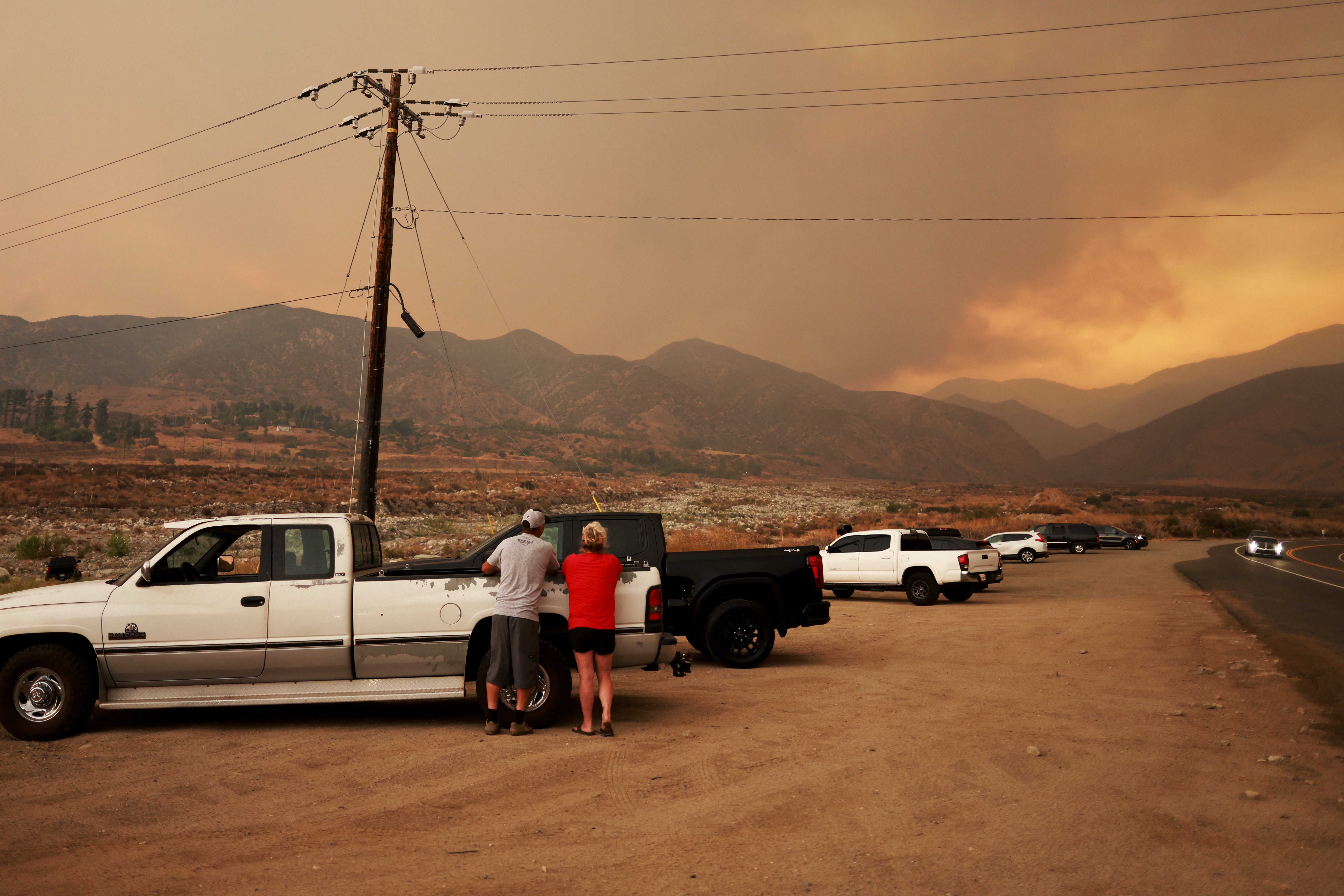 People watch the smoke column of the Line Fire as it burns near Mentone, California, on Sunday. The fire is just 3 percent contained, but it continued to grow from Sunday to Monday, jumping past 21,000 acres.