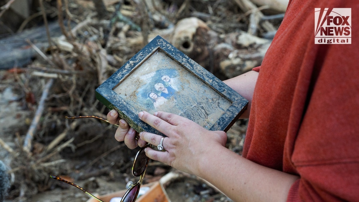 Mekenzie Craig brushes mud off a photo from her wedding that survived the mudslide that killed her in-laws on Sept. 27.