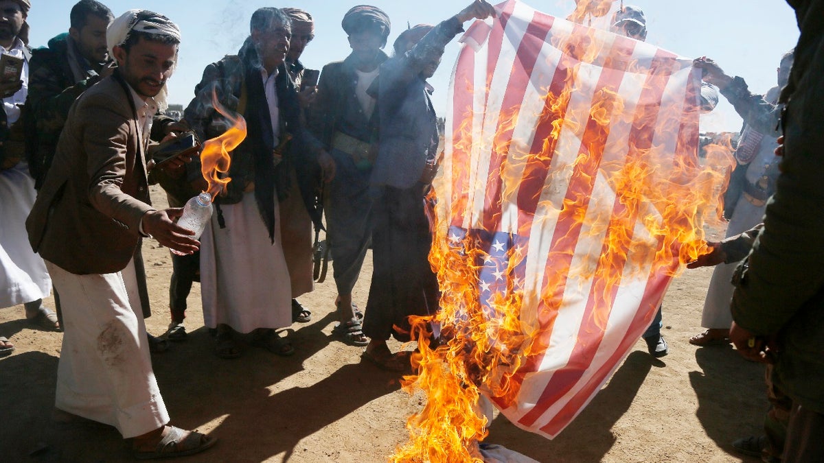 Houthi followers burn the Israeli and American flags