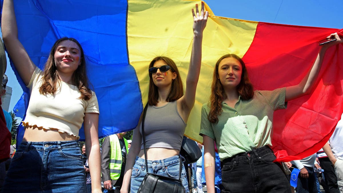 Women hold a Moldovan flag during a rally