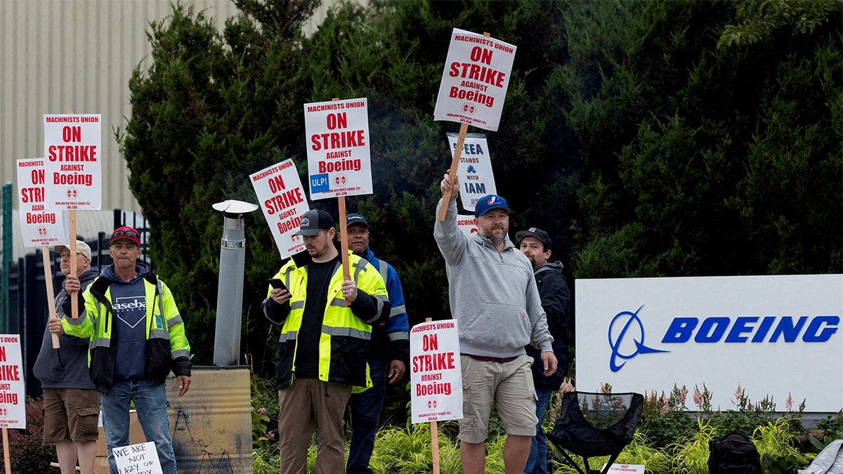 Striking union members next to Boeing sign