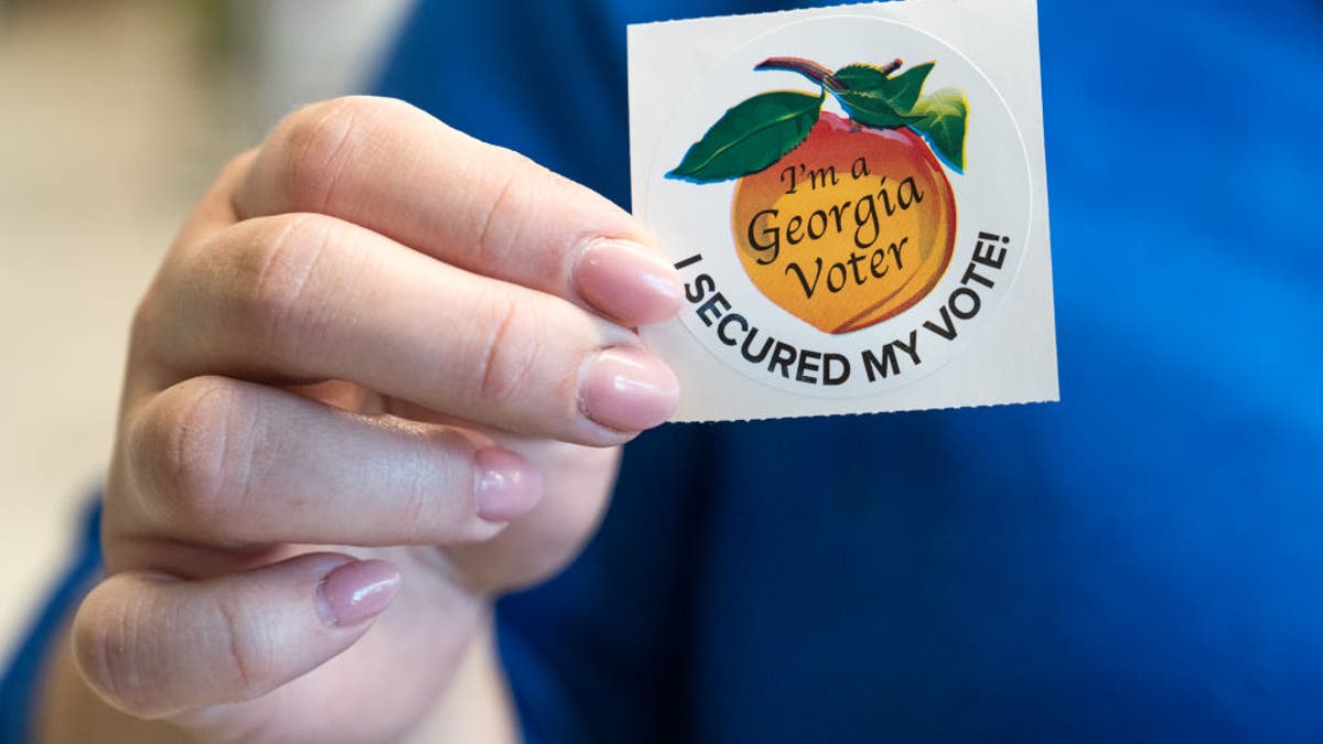 A voter holds up her sticker after casting her ballot for the Primary election on March 12, 2024 in Atlanta.