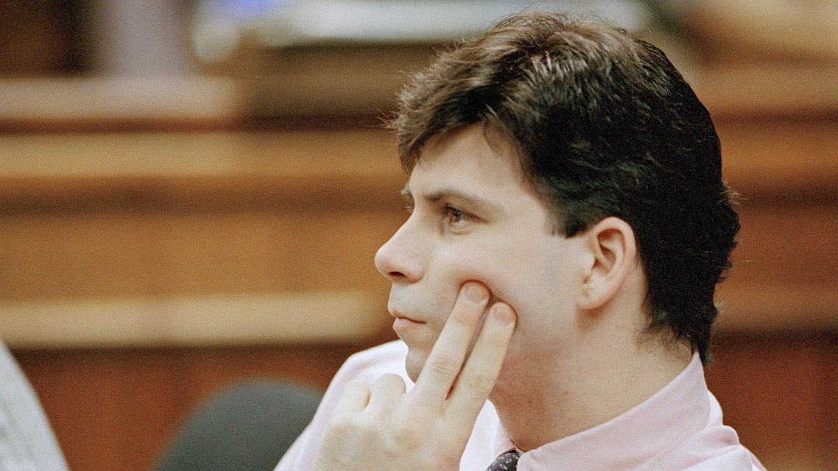 Lyle Menendez looks pensive in court holding two fingers up to his cheek