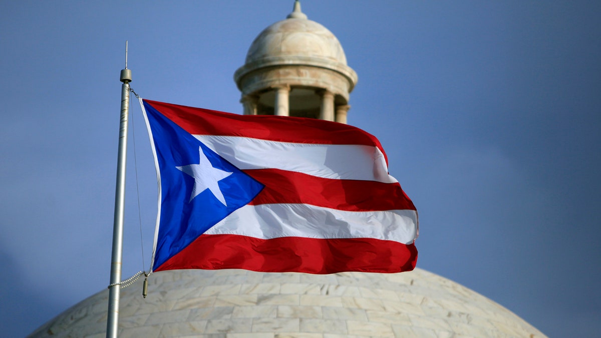 FILE - In this July 29, 2015 file photo, the Puerto Rican flag flies in front of Puerto Rico's Capitol as in San Juan, Puerto Rico. Puerto Rico's governor is pushing ahead with his top campaign promise of trying to convert the U.S. territory into a state, holding a Sunday June 11, 2017, referendum to let voters send a message to Congress. (AP Photo/Ricardo Arduengo, File)