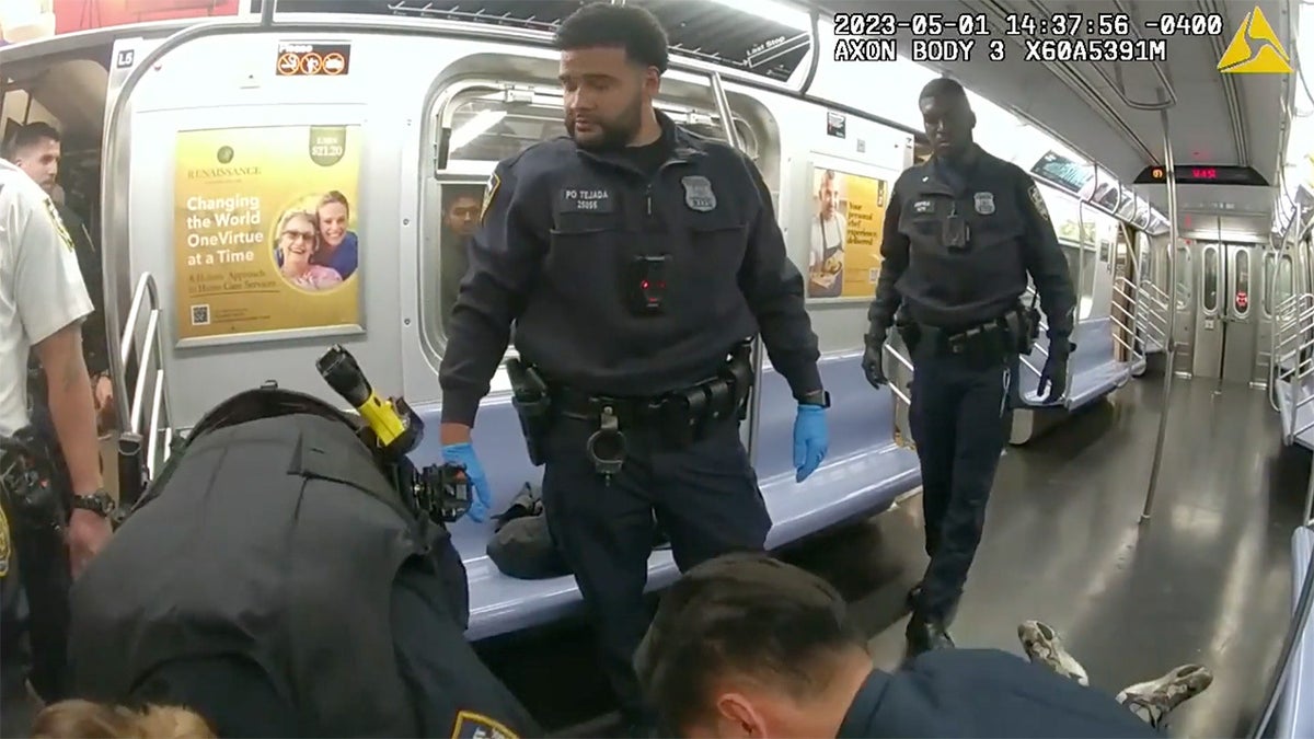 police officers on a subway car examining jordan neely, whose feet can be seen on the ground