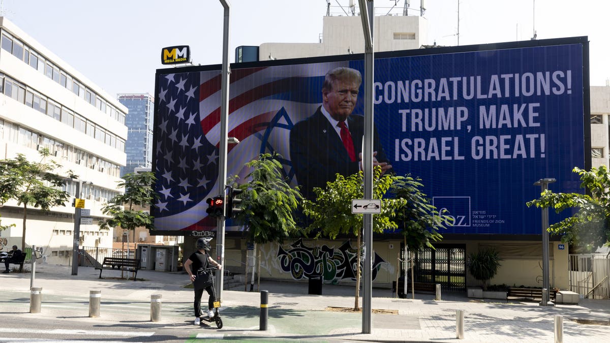 People pass by a congratulatory billboard showing elected U.S. President Donald Trump on November 7, 2024, in Tel Aviv, Israel. 