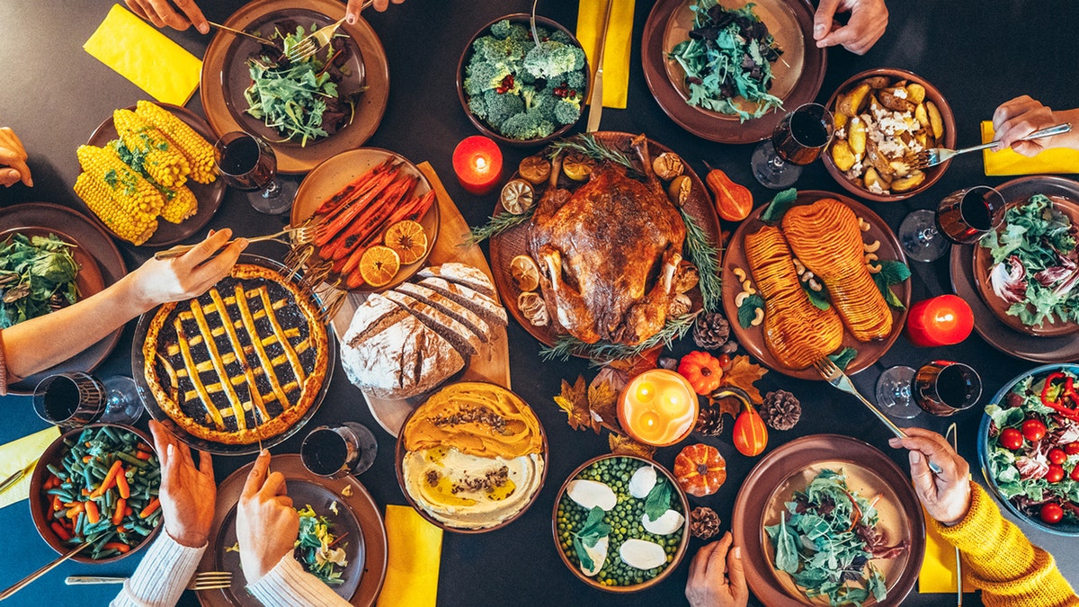 above shot of festive table with roasted turkey and food with family celebrating Thanksgiving day.