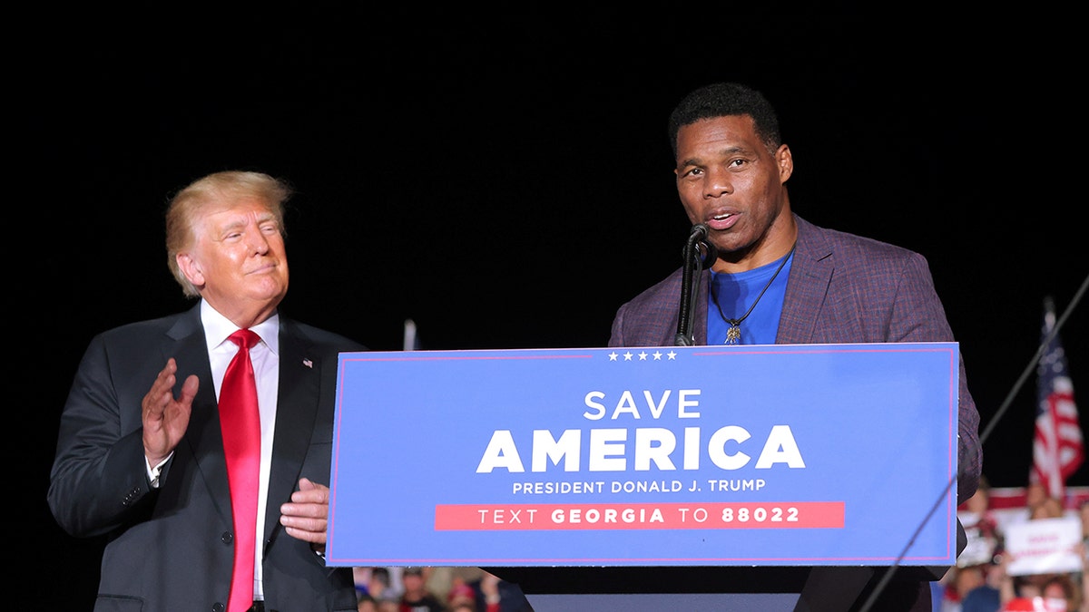 Herschel Walker, right, speaks as Donald Trump looks on