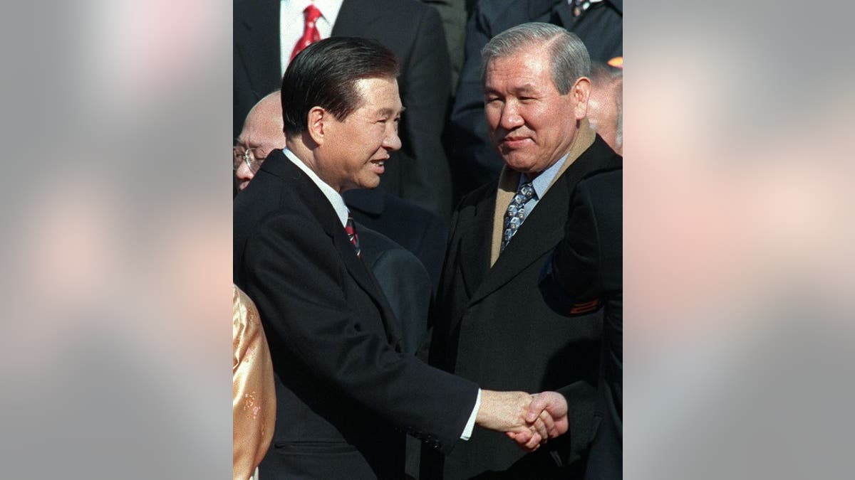 Jailed former president Roh Tae-Woo (R) looks on as South Korean new President Kim Dae-Jung (L) shakes hands with jailed former president Chun Doo-Hwan (not in picture)  before taking the oath as President during the ceremony of the Inauguration at the National Assembly in Seoul 25 February.      