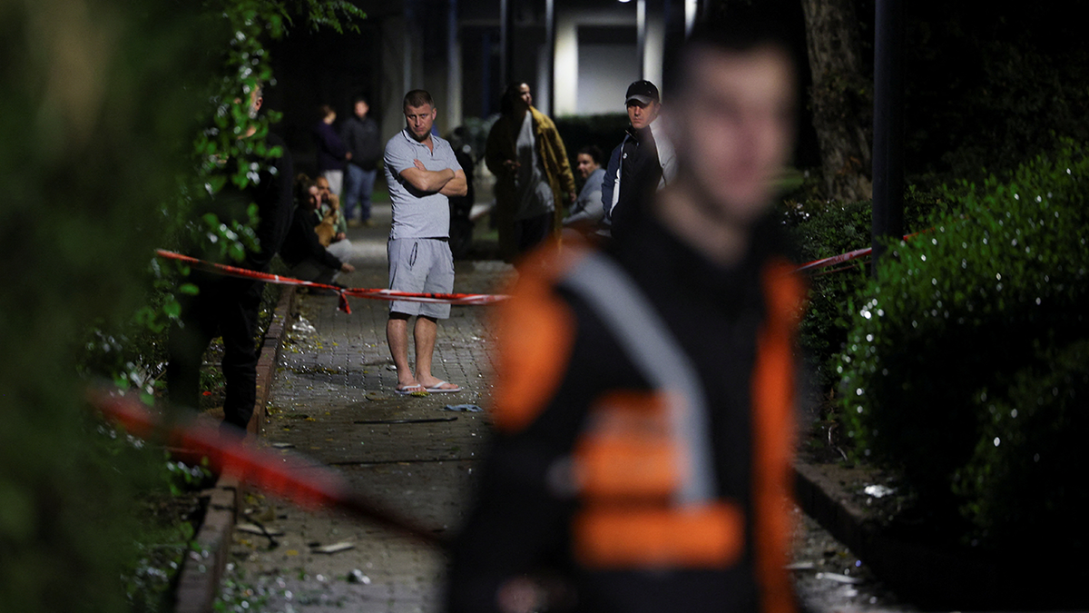 People gather at the scene of a missile strike