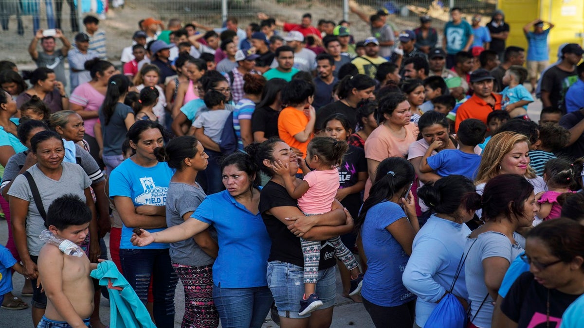 Migrants wait in line to get a meal in an encampmen