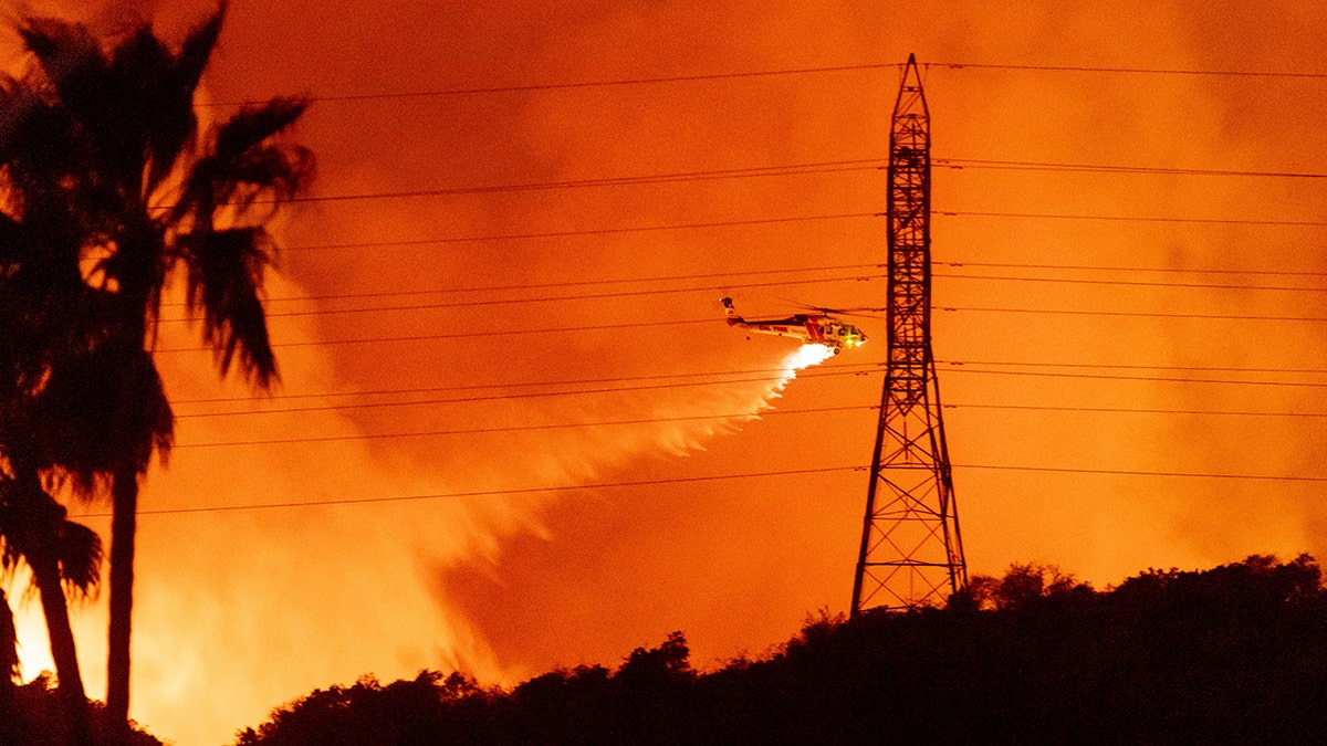 helicopter drops water on the Palisades Fire