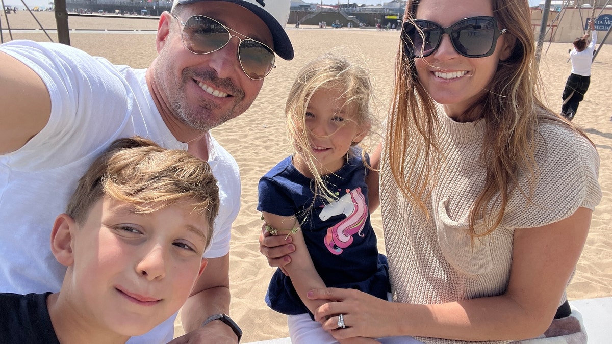 Blake Mallen poses with his wife and children on the beach.