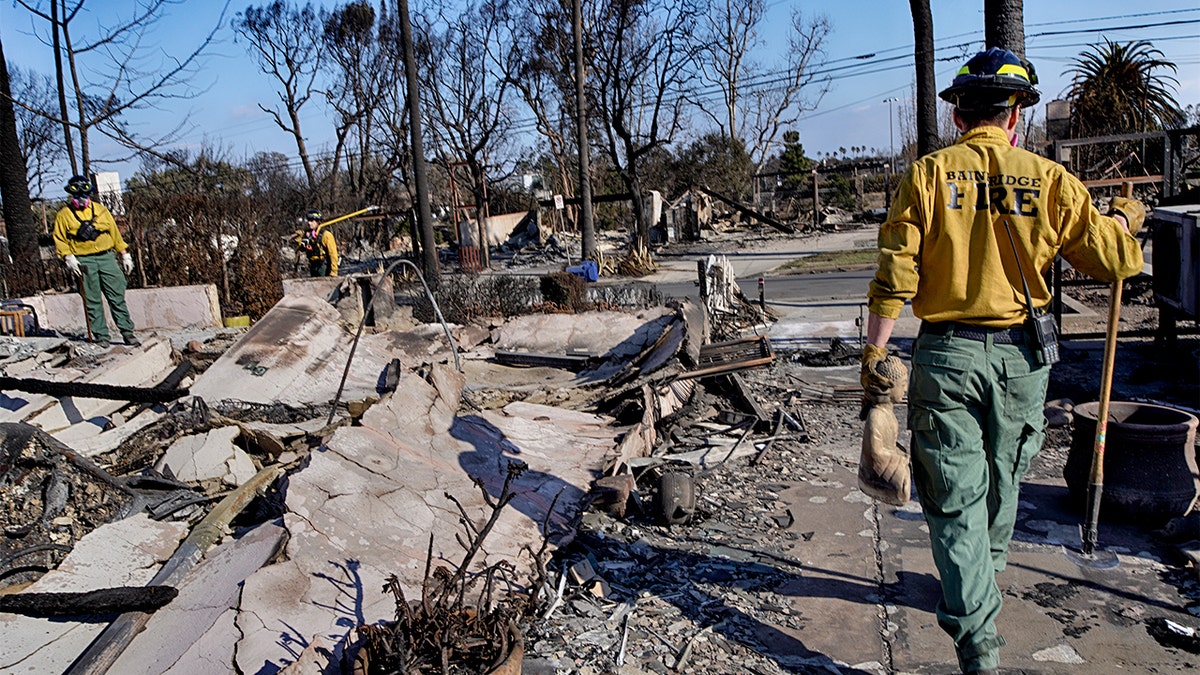 Firefighters sift through debris from a destroyed home in Los Angeles