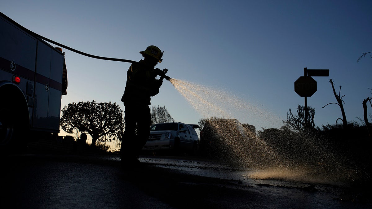 James Lyons, an engineer with the Apple Valley Fire District, sprays hot spots at a home burned by the Palisades Fire