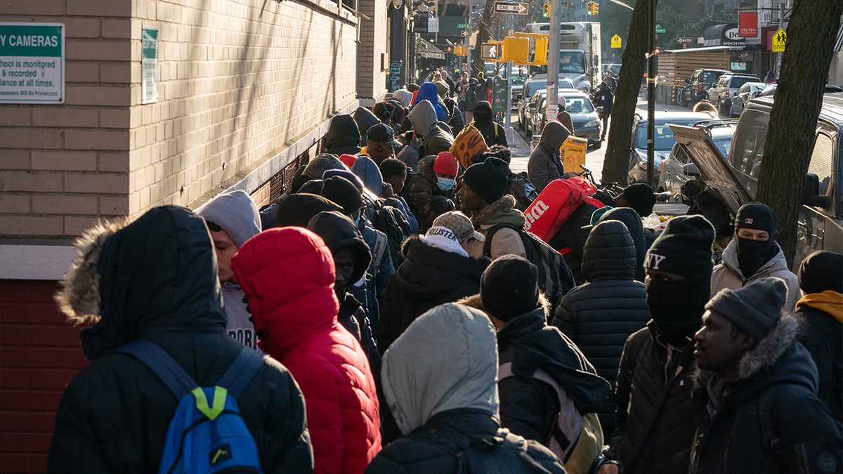 Migrants line up outside a migrant re-ticketing center