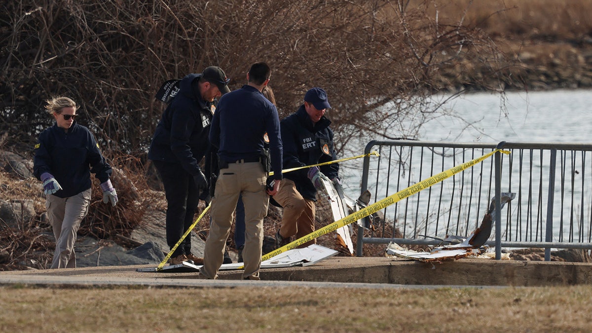 FBI agents stand near debris, after American Eagle flight 5342 collided with a Black Hawk helicopter