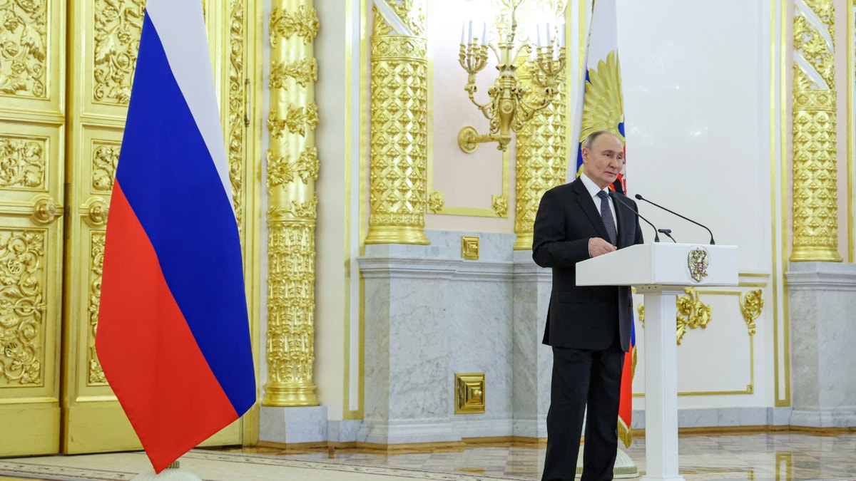 Putin at lectern in large hall with Russia flag