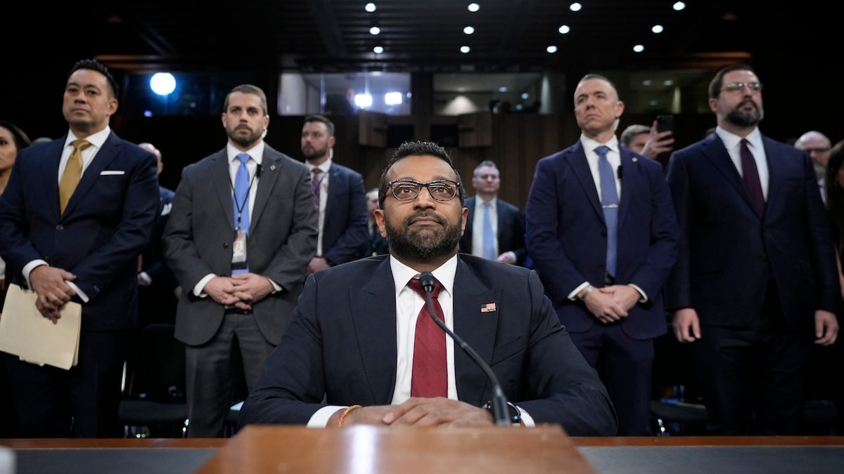 Kash Patel seated at table, others standing behind him