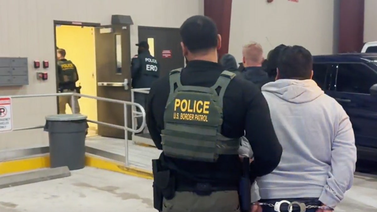 Border Patrol officer walking a person in handcuffs