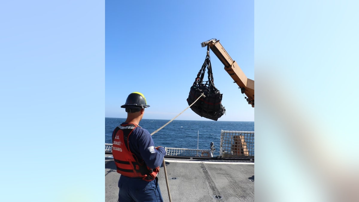 A Coast Guardsmen offloads containers of drugs