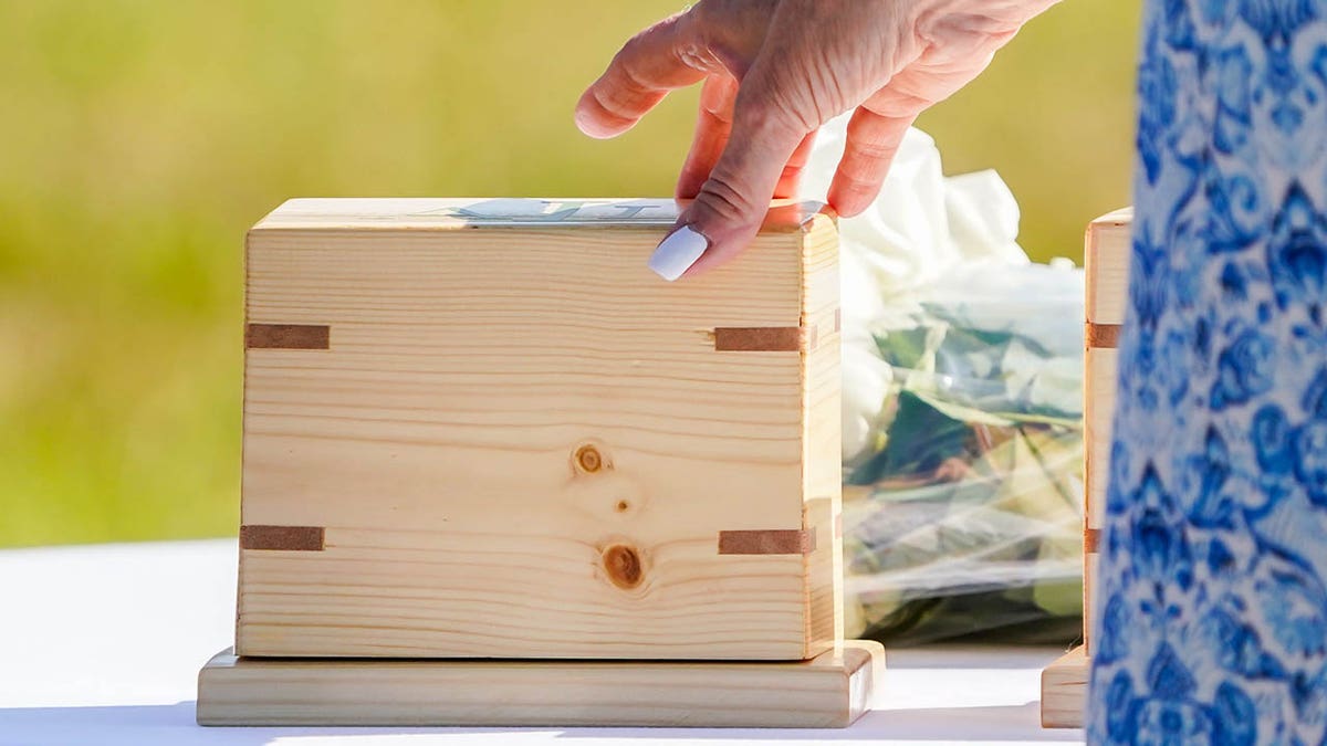 A close-up of a hand holding a wooden box.