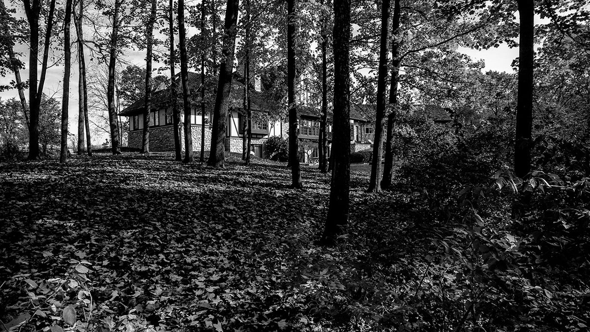 A black and white photo of Fox Hollow Farm hidden in the woods.